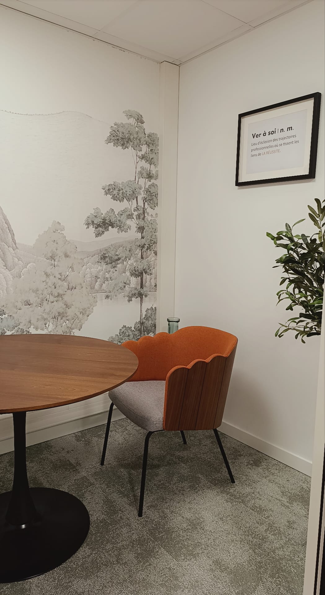 Intérieur chaleureux du cabinet au coworking de la réussite : fauteuil orange, table en bois, papier peint forêt